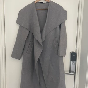 Grå kappa - Säljer en tunnare grå kappa som jag inte rikigt vet vilket märke eller butik den är ifrån. Men en fin grå kappa med öppna fickor. Säljer för 100kr eller bud!