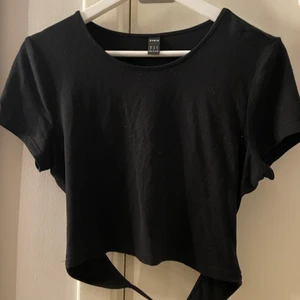 Svart topp med knytning bakom ryggen - En svart topp med en knytning längre ner till ryggen, helt oanvänd  