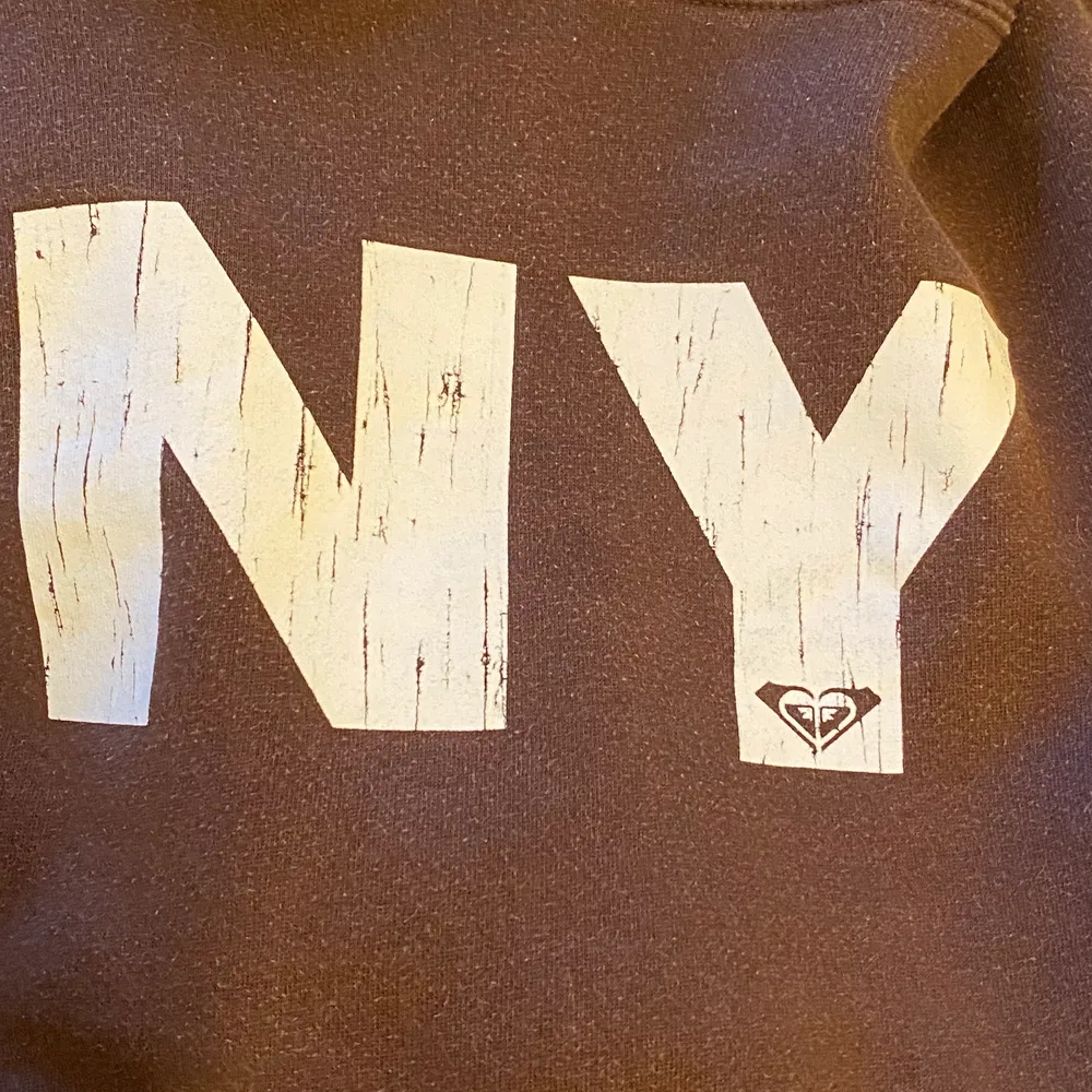 En brun hoodie i storlek L, liten i storleken så passar S, använd några gånger men i fint skick, står ”NY” på framsidan,  en bild på frihetsgudinnan vid armen, och står ”roxy” som ett liten märke baktill, ganska hårt material men välidgt fin, med ficka och luva🤎. Hoodies.
