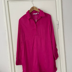 Klänning & Other Stories strlk 34 - Miniklänning/tunika från Stories. Rosa/magenta färg och blank i finishen. Passar som en miniklänning på mig som är 176 cm. 