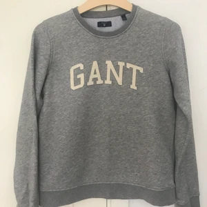 Gråmelerad GANT collegetröja stl S - Klassisk GANT collegetröja i gråmelerad material med créme vit text. Använd men i fint skick! Spårbar frakt med PostNord 66kr, eller hämtas i Kälvesta.