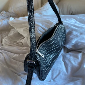 Axelväska svart - En väldigt fin och fräsch Axel väska från Nelly. Den har ett slags ormskin mönster, se bild. Bra kvalitet syns inte att den är använd. Köppte den för 300kr. Köparen står för frakt💕🌸