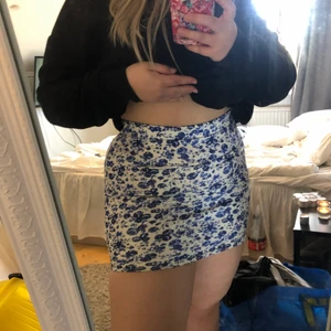 Blommig kjol - En väldigt fin kjol med blåa blommor på, den är väldigt kort så den slutar strax innan rumpan. Aldrig använd! 