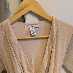 Klänning - En rosa smått glittrande klänning med v-ringning. Använd en gång och i bra skick.