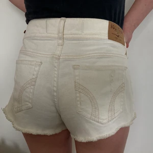 Vita Hollister shorts strl 26  - Ett par fina vita shorts från Hollister. Strl 26. De är ganska korta. Färgen är mer cremevit än vit. Perfekt på sommaren! 