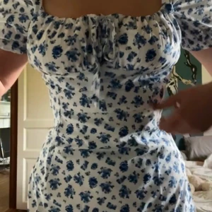 Blommig klänning blå - SÅ fin klänning! Med slits också. Aldrig använd, påsen är kvar eftersom jag råkade köpa två st och sen glömde skicka tillbaka. Är i L men sitter figurnära på mig som är medium, små storlekar.