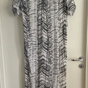 Lång skjortklänning NEW COLLECTION - Storlek M-L Lång rak skjortklänning med knäppning en bit i halsen och på ärmarna. En bröstficka och slits på sidorna.  Helt ny!