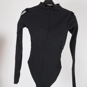 Ivy Park body - Långärmad svart body med dragkedja och lite polo från IVY PARK. I nyskick. Storlek XS. Säljer pga att jag inte använder den helt enkelt och tycker det är synd att den bara hänger, för den är såååå snygg!!!! Sitter som en smäck