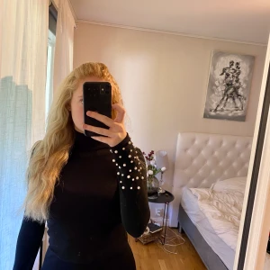 Polotröja med pärlor vid ärmarna - Svart polotröja i stretchigt skönt material, med pärlor vid ärmarna. Alla pärlor sitter kvar och tröjan är endast använd ett fåtal gånger🤍