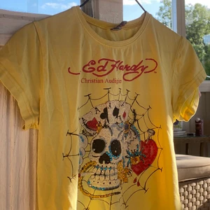 Ed Hardy t-shirt - Snygg gul vintage Ed Hardy t-shirt for WOMEN. Rhinestones samt en aning 3D i trycket. Condition 7/10. Passar M-L beroende på passning. Mått: längd 56 cm -axlar 35 cm - bröst 40 cm ⚠️Var god följ budgivningens regler ⚠️