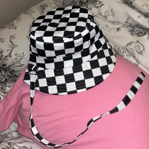 Checkered buckethat - Rutig buckethat som går att spänna under hakan (eller ta bort spännet om man vill)🖤🤍🖤 Pytteliten sminkfläck som bara är synlig på insidan, den är knappt synlig men vill ändå poängtera det istället för att inte säga nått 🌸🩷 Köpt för flera år sen 