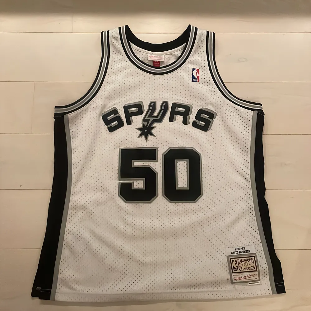 Hej,  Säljer ett San Antonio Spurs basketlinne av märket Mitchell and Ness (Hardwood classic). Linnet är i gott skick utöver två mindre hål vid främre etiketten (se bild 3). . Toppar.