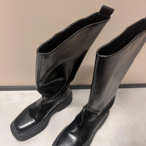 Höga svarta Boots - Säljer mina fina höga boots ifrån HM pga av för liten storlek. Använda 3 gånger, men inga defekter på skorna. Högre sula på skorna. Storlek 39. Nypris 599kr 