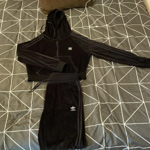 Adidas velour set - Adidas velour set med byxor och kort zip hoodie, byxorna är använda 1 gång och hoodien är oanvänd. Storlek 44 men passar mer cirka storlek 40/42.