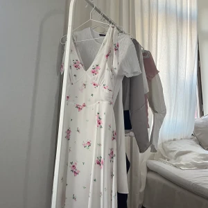 Blommig klänning  - Vit lång klänning med rosa blommor. Endast använd en gång 