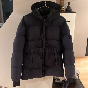 Stone Island vinterjacka junior - Stone Island junior vinterjacka i storlek 14/164. Jackan är stor storlek och passar även folk som har storlek small. Skicket är 6/10 2 defekter finns på jackan, den ena ser du i bild 3 och den andra är att en lapp på insidan är lös. Skickas på posten