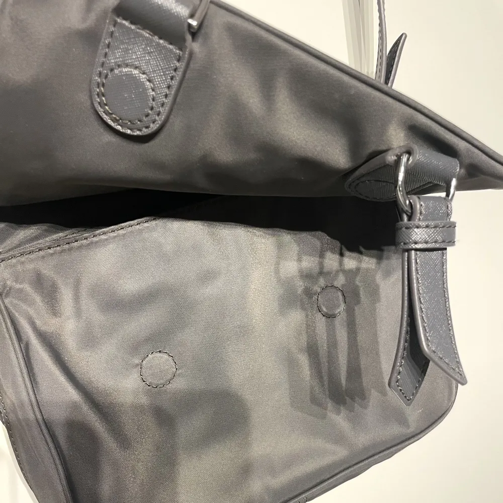 Marc Jacobs handväska köpt i New York. Modell: Nylon sling bag. Färg: Mörkgrå med silver detaljer. Justerbar axelrem, magnet knäppe på locket, ett fack på insidan. Endast använd ca 2 gånger.  Nypris ca 2000kr.. Väskor.