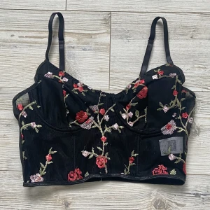 Blommig korsett topp - Blommig korsett topp i nyskick 🖤 Kuporna är inte genomskinliga och axelbanden är justerbara. Passar nog A-C kupa. Fri frakt till 10 september!!