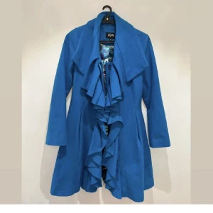 Kappa  - Superfin kappa med volang och med en läcker foder. Färgen är svår att visa men den är turkos. 