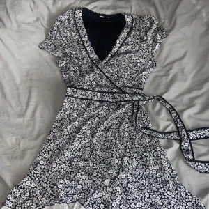 Blommig Svart vit omlottklänning  - Orginalpris 400kr, andvänt ett fåtal gånger, jätte skönt matrial.