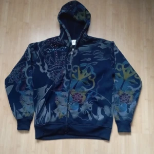 Ed Hardy liknande tröja - Skitsnygg hoodie som ja köpt på vinted men tyvärr aldrig använt! Tröjan är ljusare i verkligheten! Va ja kan se finns inga defekter ba lite trög dragkedja!. Bara fråga för flera bilder!
