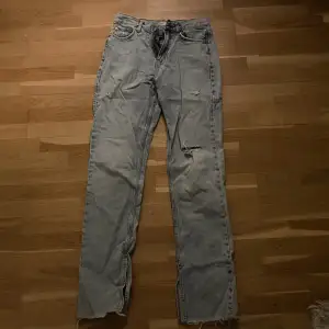 Ett par high waisted jeans från Gina tricot strl 36. Hålen och slitsen är en del av designen
