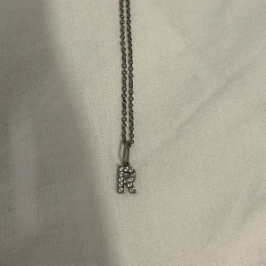 Ioaku R halsband - Ioaku bokstavshalsband (R)  Säljer pågrund av att den inte längre kommer till användning, har använt ett fåtal gånger och den har tappat färgen lite men inget som man tänker mycket på, nypris 399 mitt pris 200