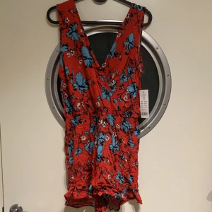 Helt ny playsuit - Röd playsuit med blå blommor. Köpte denna inför resa som inte blev av :/ ord. Pris 249 kr