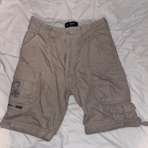 brandit shorts - Brandit cargo shorts i färgen beige.  Säljer då den inte kommer till användning. Säljs i butik för 699kr