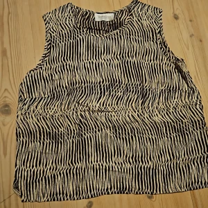 Tanktop - Svart Tanktop med beiga mönster. Tunt material.  Står ingen storlek men tror det är S eller M