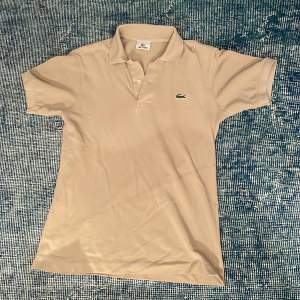 Säljer beige Lacoste pikétröja i nyskick. Nypris 1300kr