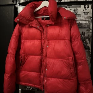 Bikbok jacka (med avtagbar luva) - Röd bikbok jacka i storlek M (passar både mindre och större beroende på hur man vill ha den)  I bra skick förutom små fläckar vid armarnas slut. Ej testat att tvätta bort det med vanish eller liknande så kan lika väl gå bort :) Därav det billigare priset!