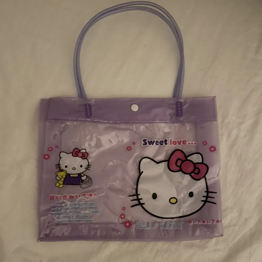 Genomskinlig väska med plastframsida med Hello Kitty-motiv köpt för några år sen. Har legat i en påse med andra väskor i nåt år så den är lite skrynklig, men inga permanenta skador ☺️  Mått: 28x23cm. Obs: Inte äkta Sanrio-merch :P. Väskor.