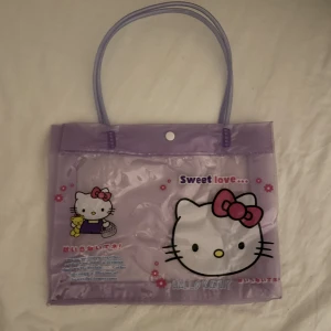 Hello Kitty väska - Genomskinlig väska med plastframsida med Hello Kitty-motiv köpt för några år sen. Har legat i en påse med andra väskor i nåt år så den är lite skrynklig, men inga permanenta skador ☺️  Mått: 28x23cm. Obs: Inte äkta Sanrio-merch :P