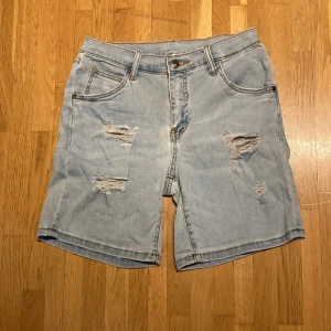 Jeansshorts  - Stretchiga shorts med hål Hög midja  Ljus röd fläck vi höger bakficka Kanske går bort i tvätten 