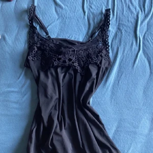 Svart linne - Sött linne med spetsdetaljer. Ställbara axelband. 