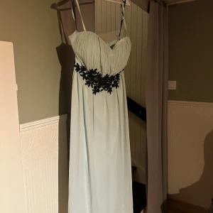 Mintgrön klänning - mintgrön klänning med svarta spetsdetaljer vid midjan använd en gång finns löstagbara axelband  