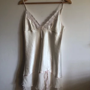 Vit klänning - Vit klännimg/ nattlinne! Har fina rosa detaljer både på bysten och på nedre delen av klänningen! Klänningen är i ett siden liknande material! 