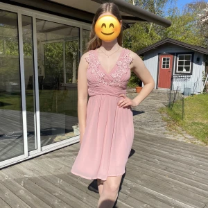 Rosa klänning med blommor - Rosa klänning med blomdetaljer, använd 2 gånger, finns en pytteliten fläck vid ena bröstet där tyget är veckat och den sitter precis under en blomma så ingenting man tänker på, från Bubbleroom