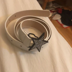 Bälte med en stjärna  - Ett vit bälte med en stjärna i jätte bra skick går att göra fler hål i om behövs använd en gång!