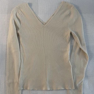 Supersöt v-ringad tröja - Ribbad/stickad mjuk tröja. Superbra nu till hösten, enkel och snygg. Snygg v-ringning både fram och bak. Varm ljus begie färg. Finns tecken på användning men generellt i bra skick. 