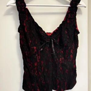 Fin röd topp med svart spets - Röd topp med svarta spets detaljer sexigt och gulligt på samma gång, dragkedja i ryggen storlek 42 men passar M/L 