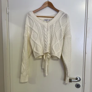 Vit stickad med rosetter - Stickad tröja med rosetter i ryggen. Använt några gånger men är i bra skick 