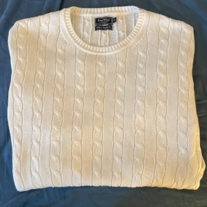 Kabelstickad tröja  - En vit Kabelstickad tröja från East. Tröjan är i utmärkt skick och har inga hål eller andra defekter. Storlek M. Perfekt nu till vintern. Gjord av 100% bomull. Hör av dig för fler bilder eller frågor. Gratis frakt!