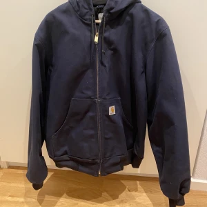 Carhartt jacka, strl S - Säljer min marinblå carhartt jacka pga lite användning. Jackan är något fodrad inuti så håller ändå värme. Den är köpt och tillverkad i USA och använd ett fåtal gånger. Jag är ca 170 och på mig sitter den lite oversized! Nypris 2500kr