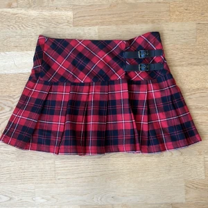 Röd rutig miniskirt - Dethär är den coolaste kjolen jag äger! Det är en miniskirt med läderspännen vid sidan som gör den såååå tuff och punkig. Den har också en dragkedja som knappt syns vid sidan. Den är pleated och passar perfekt med fishnets! Hur cool?!✨⛓️🍄