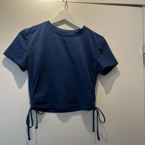 Blå topp - Blå topp med knytningar på sidorna. I mycket fint skick. Knappast använd 