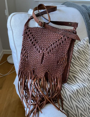 Superfin Vintage Skinnväska Braided fransar  - Vintage läder skinn axelremsväska  Härlig väskan med snygg patina  Reglerbar axelrem Ofodrad Stängs med en dragkedja Det finns lite märken men i bra skick  Bredd 26cm Höjd 25cm