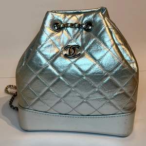 Chanel Gabrielle inspirerad ryggsäck i storlek small. Silver färgat skinn med guld och silver oxiderat hardware. Mått: 20.3 x 8.3 x 15.2 cm  Bästa kvalité med kommer dust bag. 