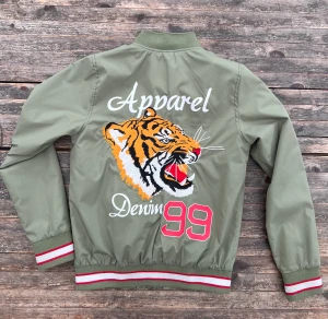 Vingino Jacka vind jacka - Tuff vindjack med stort tigertryck på ryggen. Storlek 14 ( ca 158-164cm ) skulle jag tippa på.  Fint skick Kontakta gärna för mer bilder eller frågor😊